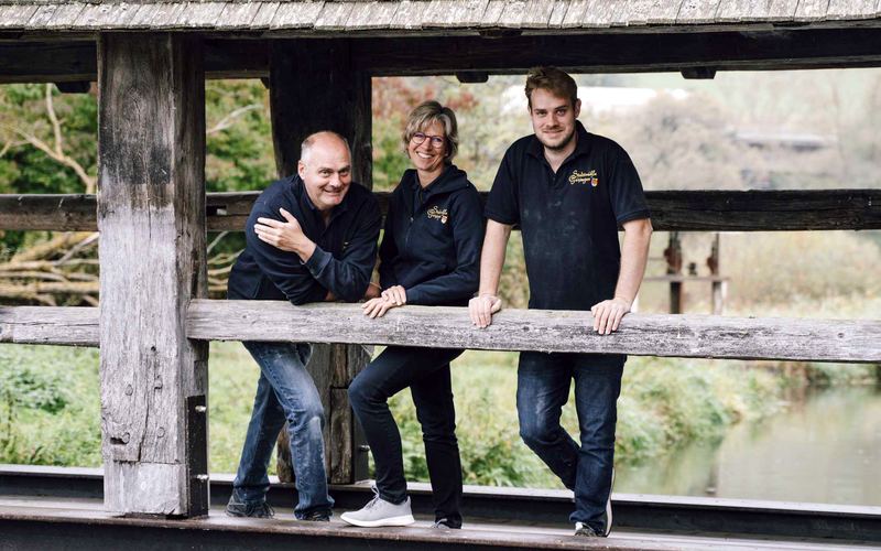 Die Familie der Stadtmühle Geisingen an der Brüstung einer überdachten Holzbrücke in Geisingen